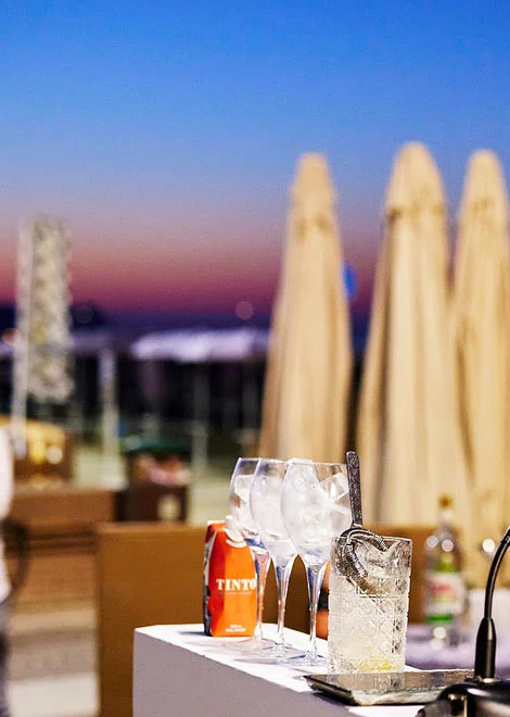 L'angolo di un bancone portatile con i bicchieri, davanti al mare al tramonto