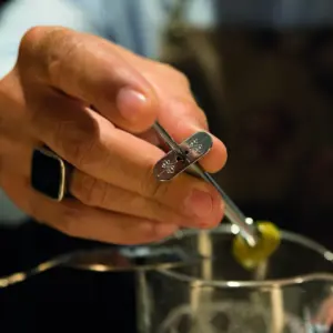 Acchiappafrutta The Bars che posa un oliva sul drink