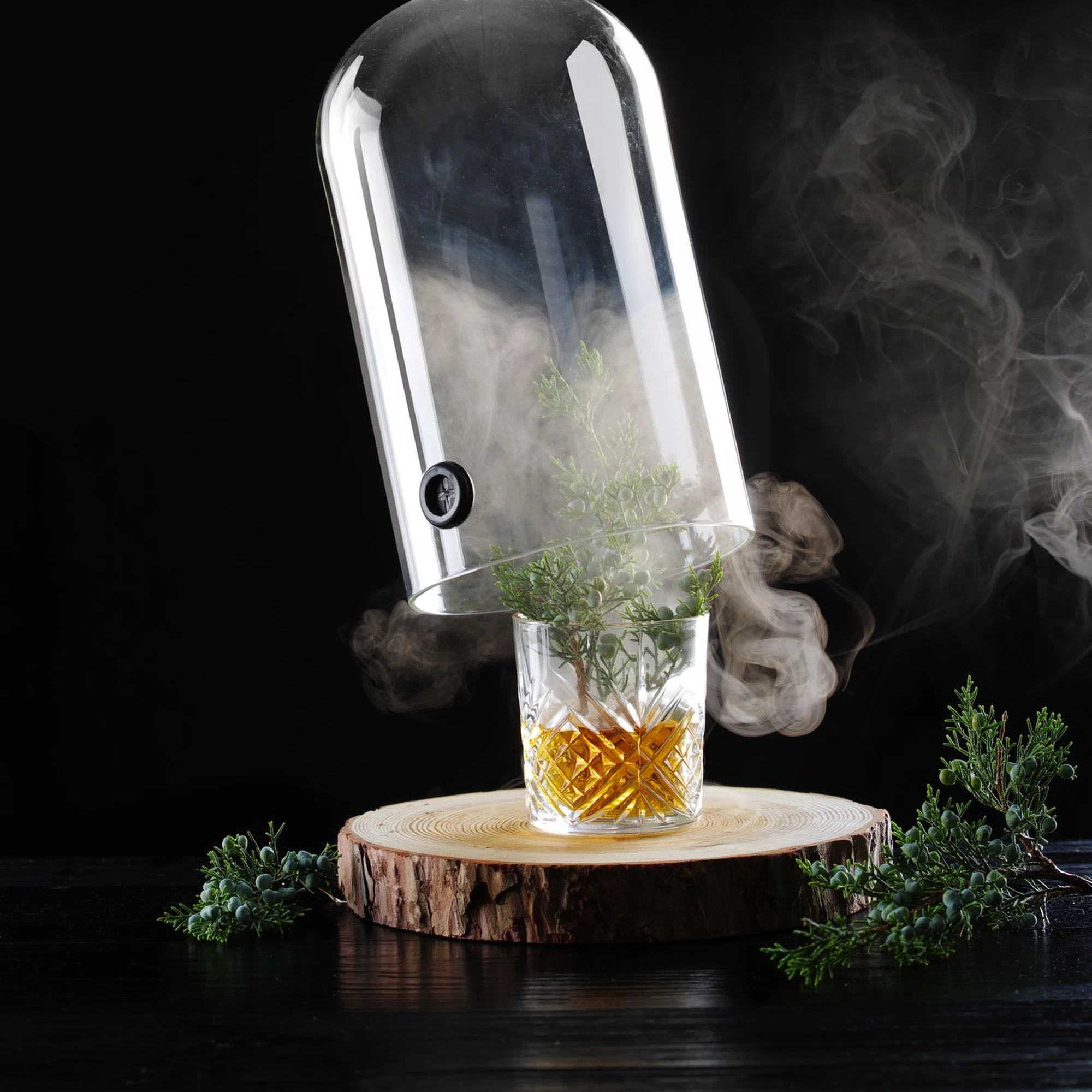 Campana in vetro sollevata sul cocktail affumicato al ginepro