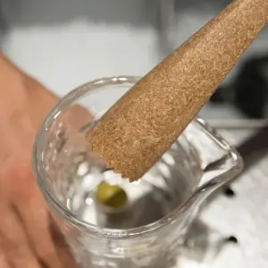 Muddler ergonomico zigrinato in eco legno The Bars mentre pesta la frutta nel mixing glass