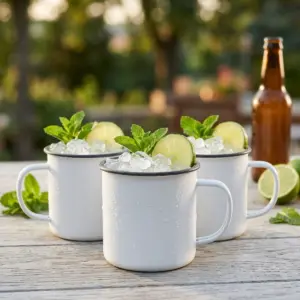Enamel bianca: tre tazze The Bars da 45 cl con Moscow Mule, lime e menta, su un tavolo all'aperto