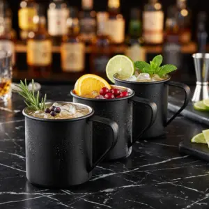 Enamel nera: tre tazze The Bars con Moscow Mule, ghiaccio e guarnizioni, sul bancone in marmo nero